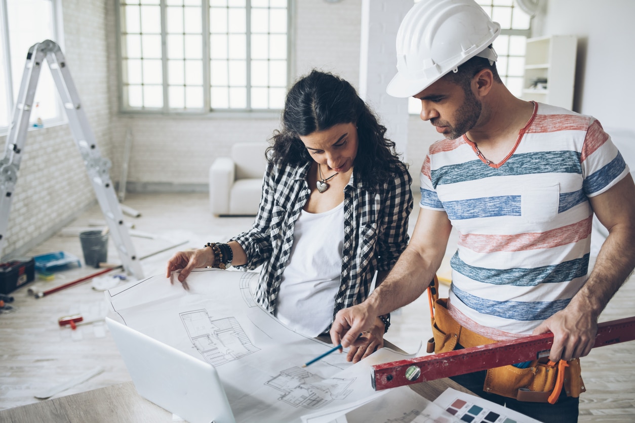 Young woman and construction worker looking at blueprints